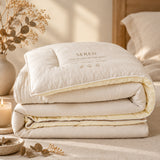A folded beige quilted comforter with white tags attached, photographed on a clean white studio background.