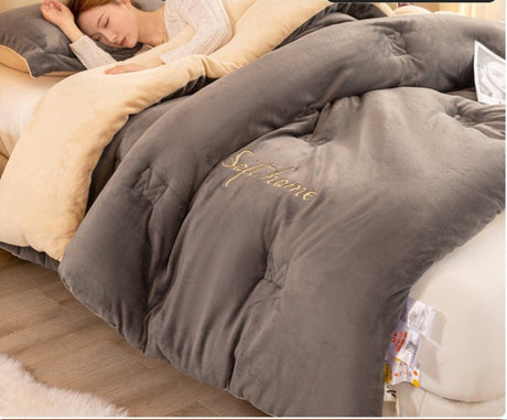 Gray comforter with 'Soft Home' branding on a bed, with a person partially visible.