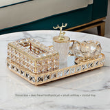 Decorative set with tissue box, deer head toothpick jar, small ashtray, and crystal tray on a marble surface.