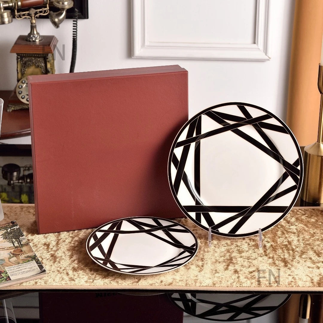 Two black and white patterned plates on a table with a red box in the background.