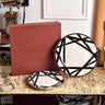 Two black and white patterned plates on a table with a red box in the background.