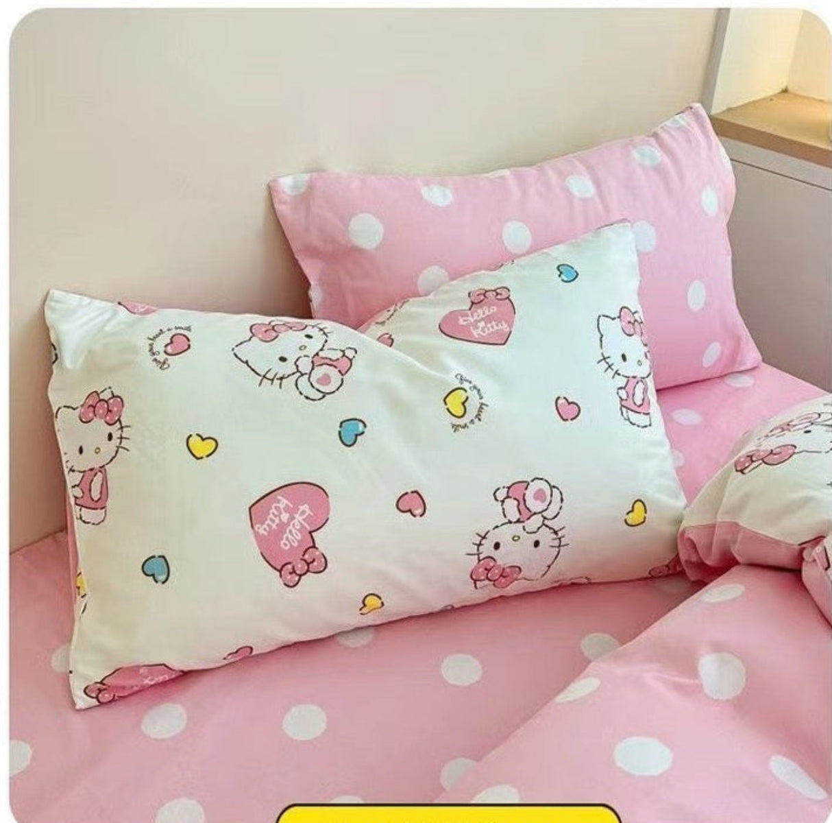 Pink polka dot bedding set with cartoon character pillow on a bed.