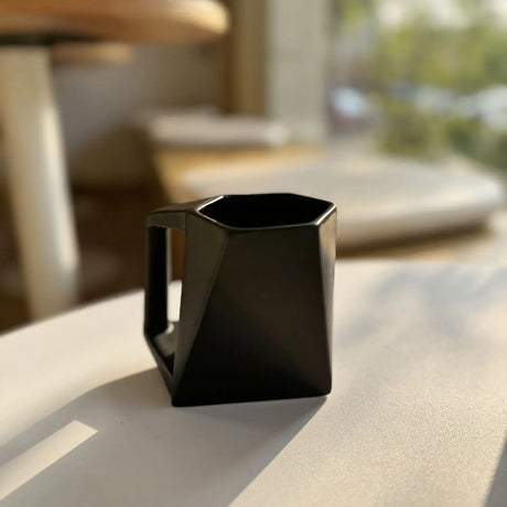 Black ceramic pitcher on a table with a blurred outdoor background