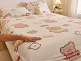 Bedding set with teddy bear design on a bed, featuring a hand touching the fabric.