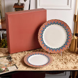 Two decorative plates with a colorful zigzag pattern on a table next to a red box.