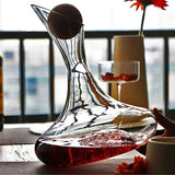 Clear glass wine decanter with red liquid on a table with a blurred background
