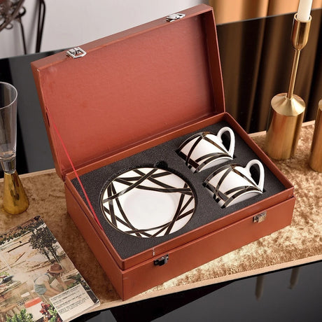 Set of ceramic tea cups and saucers in a brown leather box on a decorative table.