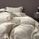 Beige textured bedding set with lace details on a bed against a dark wall.