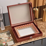Open wooden jewelry box with decorative interior on a table.