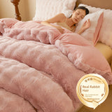 Person sleeping under a fluffy pink comforter with a 'Real Rabbit Hair' label in the corner.