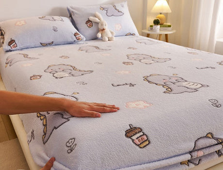 Bedding set with cartoon designs on a bed, featuring a hand touching the fabric.