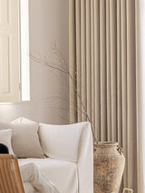 Beige curtains with a white sofa and decorative vase in a room.