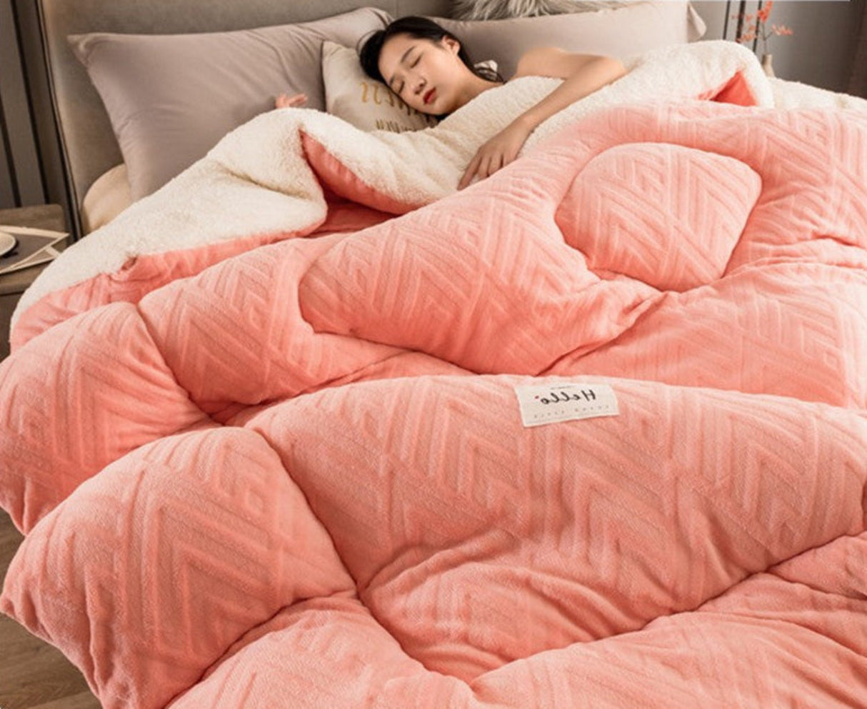 Person sleeping under a pink comforter with a brand label in a bedroom setting