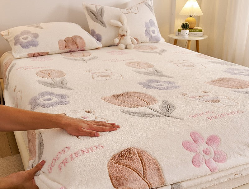 Floral and animal patterned bedspread on a bed with a hand touching it, in a bedroom setting.