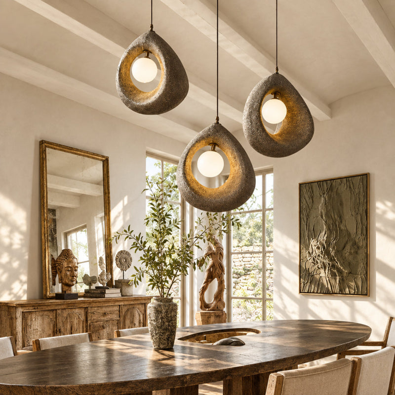 Modern dining room with hanging concrete pendant lights, wooden table, and decor.