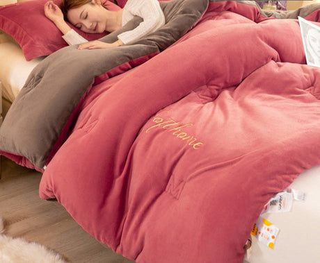 Pink comforter with text on a bed, showing texture and use scenarios.