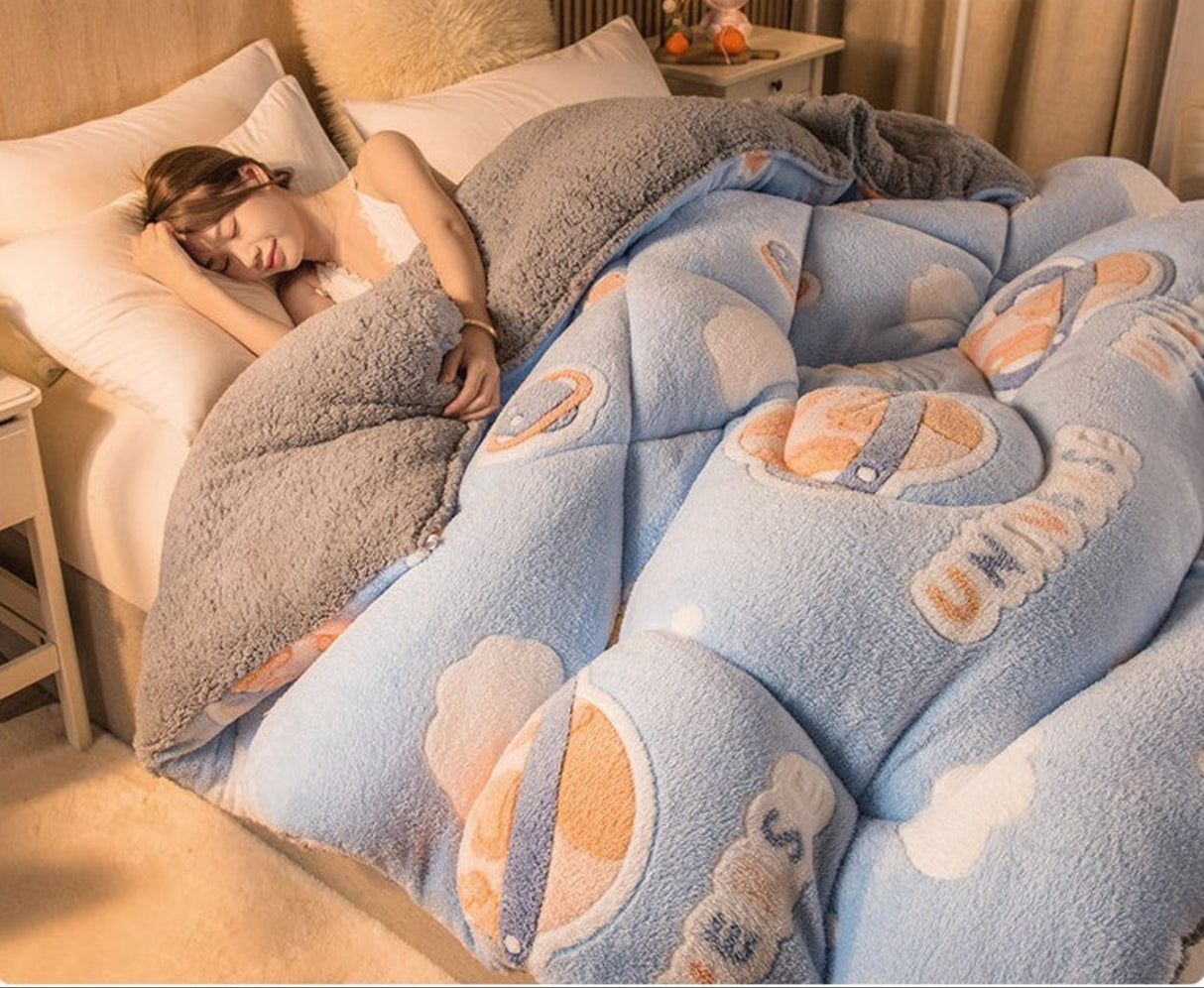 Person lying in bed under a blue cartoon-themed blanket with cloud designs.