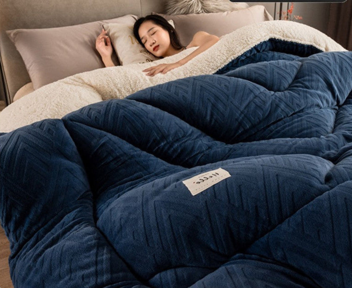 Person lying in bed under a blue comforter with a visible brand label.