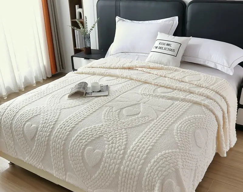 Bed with white textured blanket and pillows in a bedroom setting
