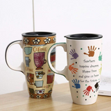 Two mugs on a wooden surface with one featuring coffee-themed designs and the other with handprints and text.