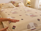 Beige bedspread with cartoon dog design on a bed, with a hand touching it.