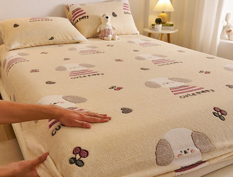 Beige bedspread with cartoon dog design on a bed, with a hand touching it.