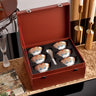 Set of ceramic tea cups with a decorative interior in a red box on a table.