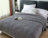 Gray textured blanket on a bed with white pillows in a bedroom setting