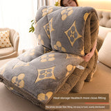 Person holding a large gray and brown patterned blanket in a living room.