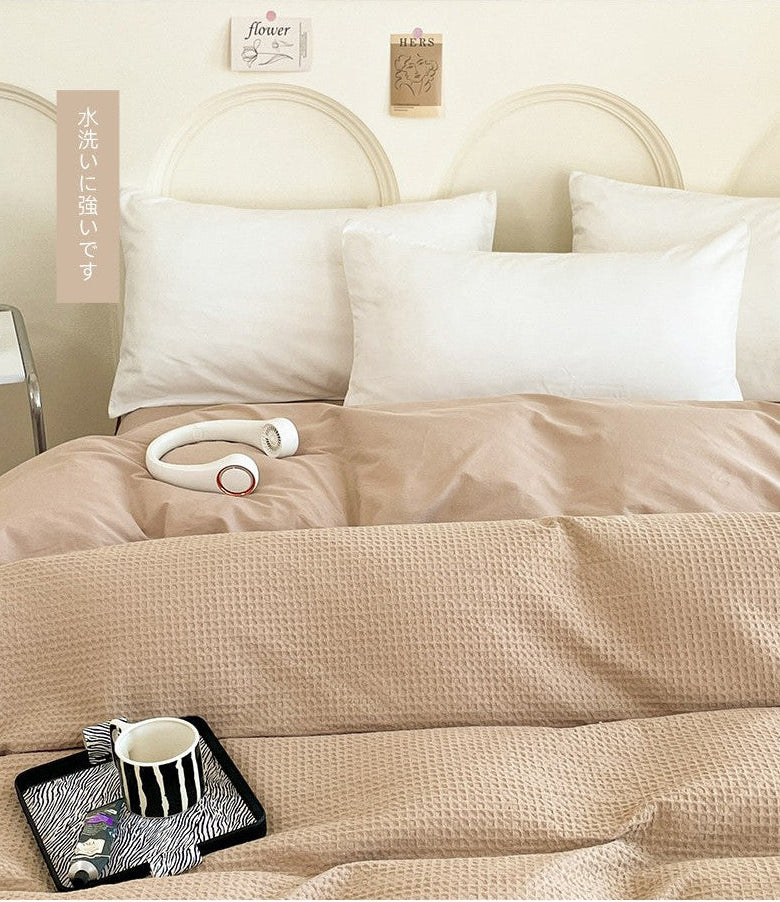 Beige bedding set with a headboard and pillows on a bed.