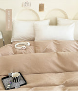Beige bedding set with a headboard and pillows on a bed.