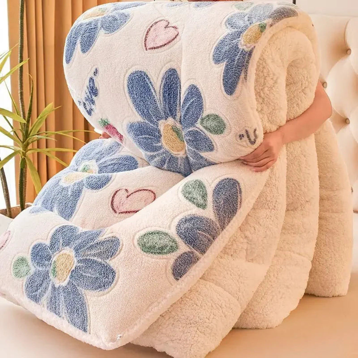 Floral-patterned blanket with blue flowers and pink hearts being held by a person.