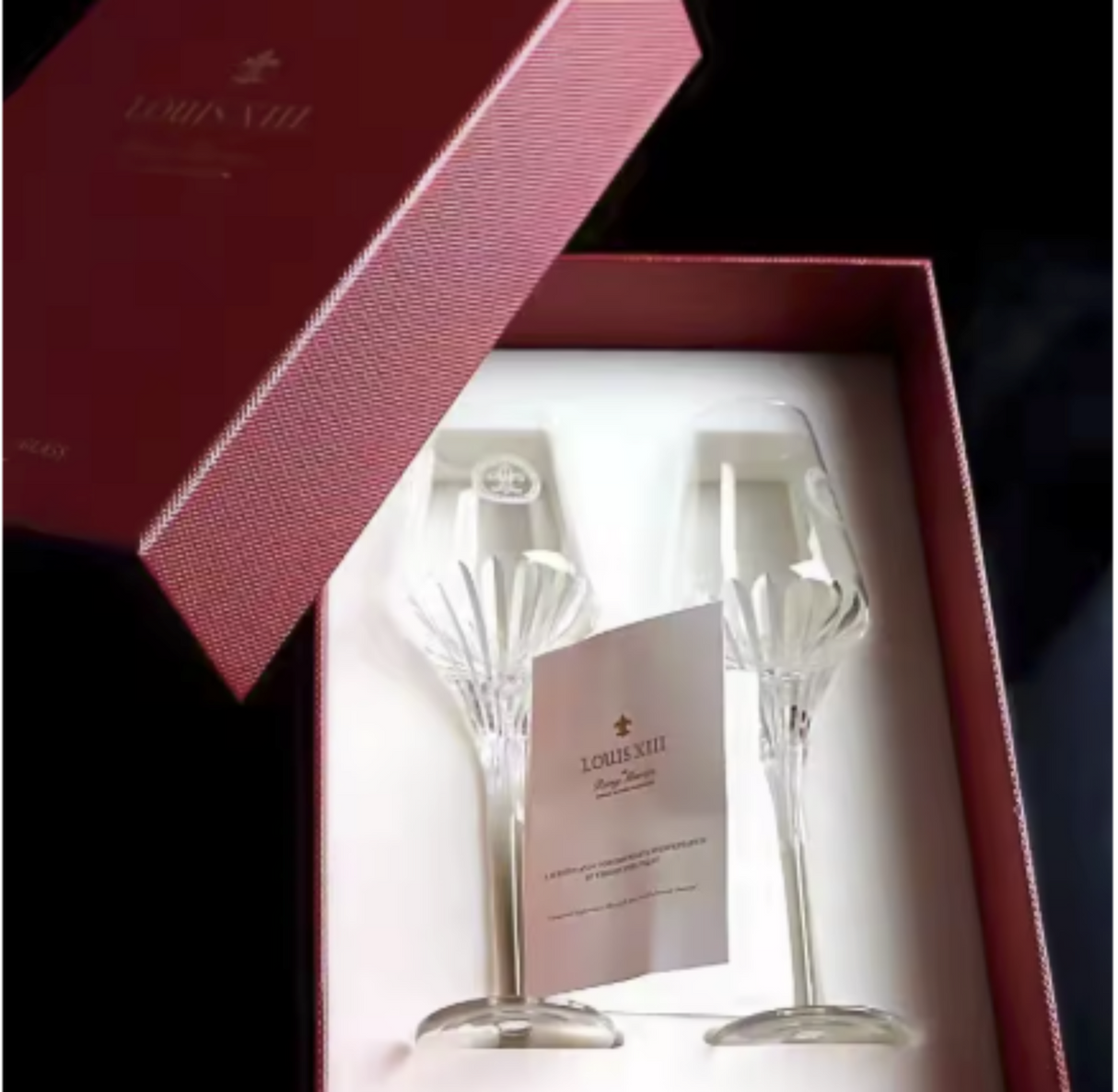 Two crystal champagne flutes in a Louis XIII box with a card inside.