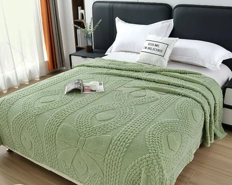 Green blanket on a bed with white pillows in a bedroom setting