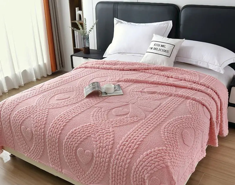 Pink blanket on a bed with pillows and a book in a bedroom setting