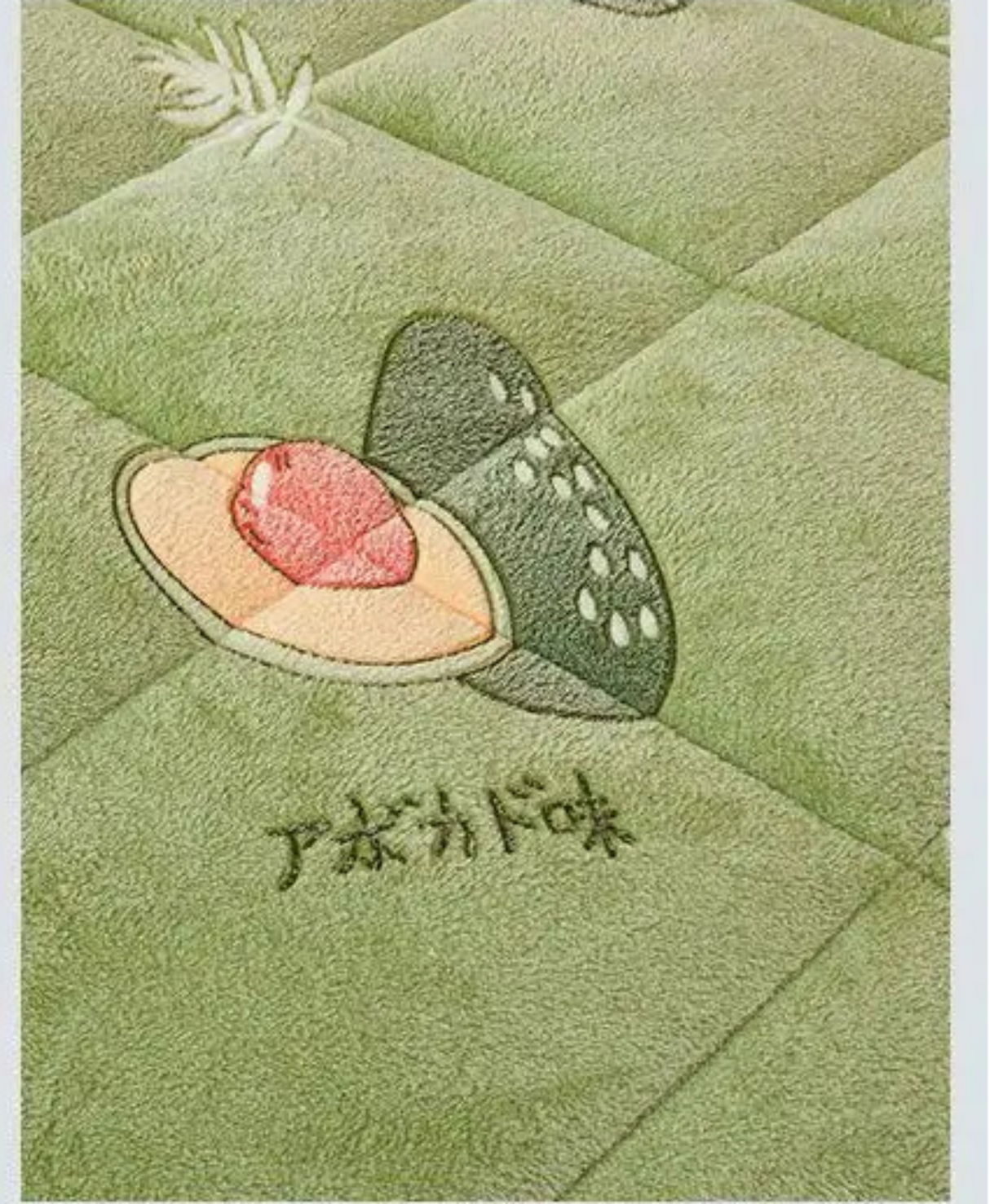 Product comparison between two versions of a green quilt with embroidered design on a light gray background.