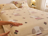 Beige bedspread with cartoon dog design on a bed, with a hand touching it.