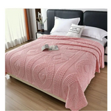 Pink blanket on a bed with white pillows in a bedroom setting