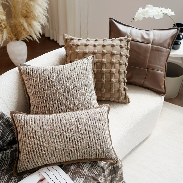 Three textured pillows on a white sofa with decorative plants in the background