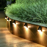 Row of outdoor lights embedded in a stone path with grass above.