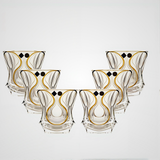 Set of six decorative glass tumblers with gold and black patterns on a white background