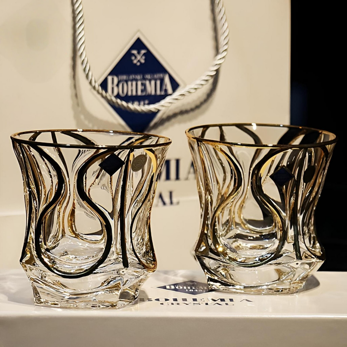 Two crystal glasses with swirl design in front of a Bohemia glassware logo.