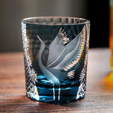 Decorative glass with bird etching on a wooden surface