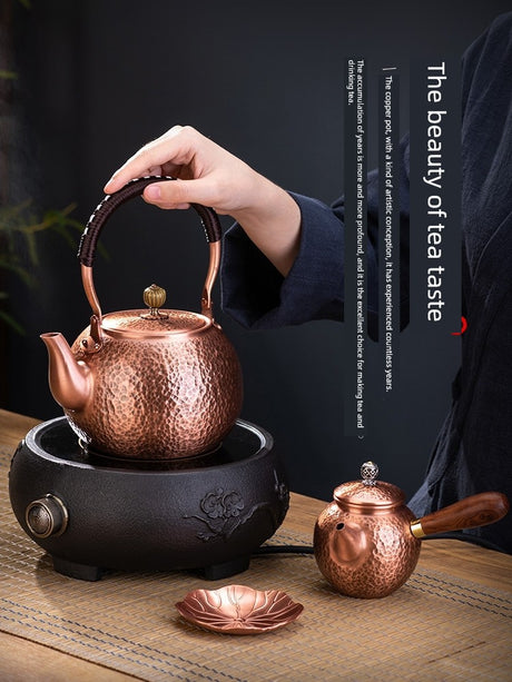 Copper teapot on a black electric heating plate with a blurred background
