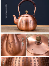 Copper teapot with intricate designs on a dark background