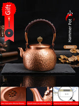 Copper teapot with handle on a dark surface, labeled as a gift item.