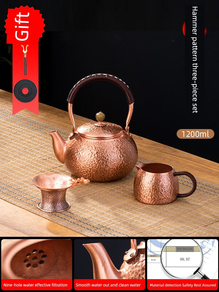Copper tea set with teapot, cup, and strainer on a wooden surface with a dark background.