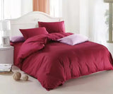 Maroon bedding set on a bed with white headboard and light-colored floor.
