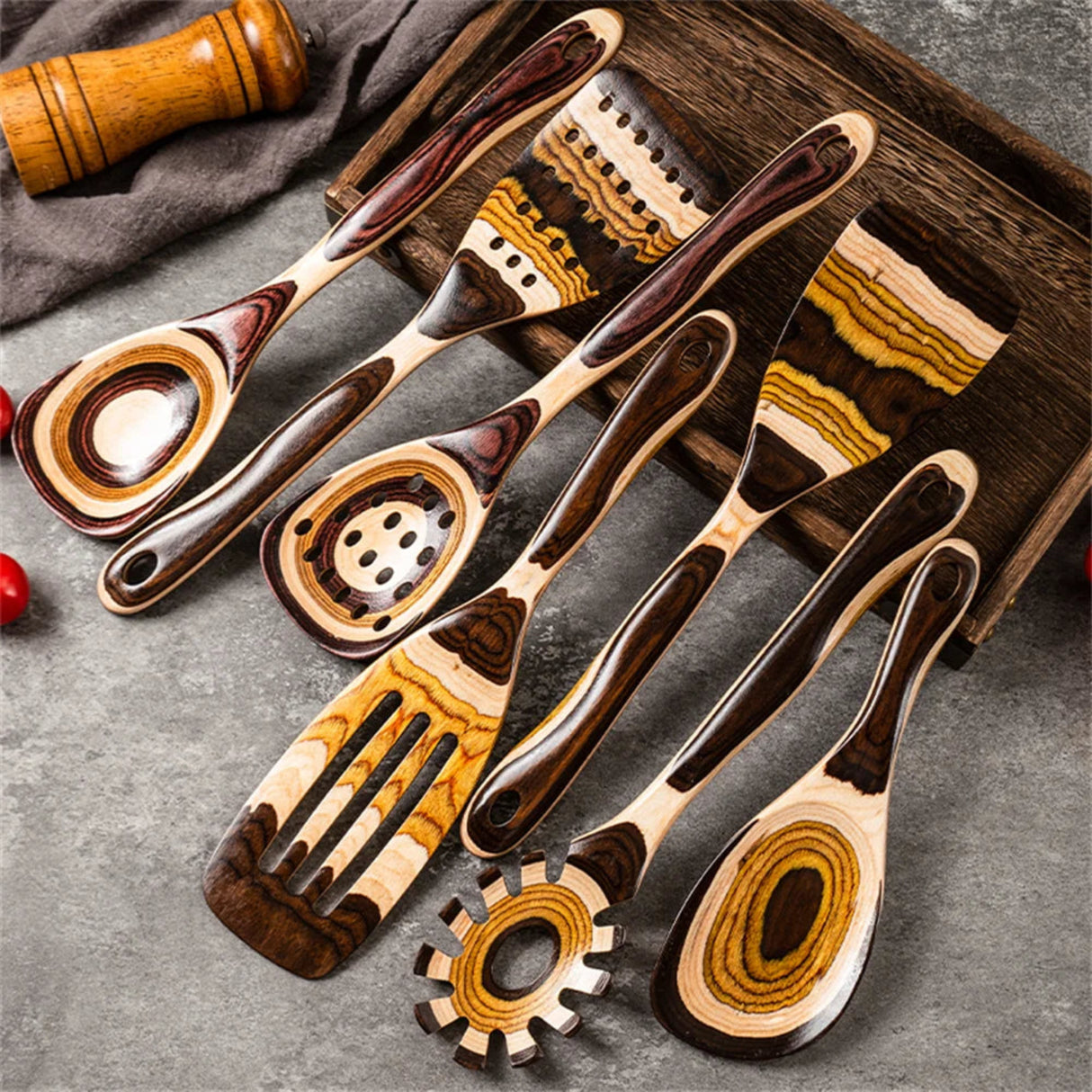 Set of wooden kitchen utensils on a gray surface with a wooden tray.