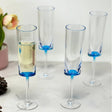Set of four champagne flutes with blue accents on a marble surface.